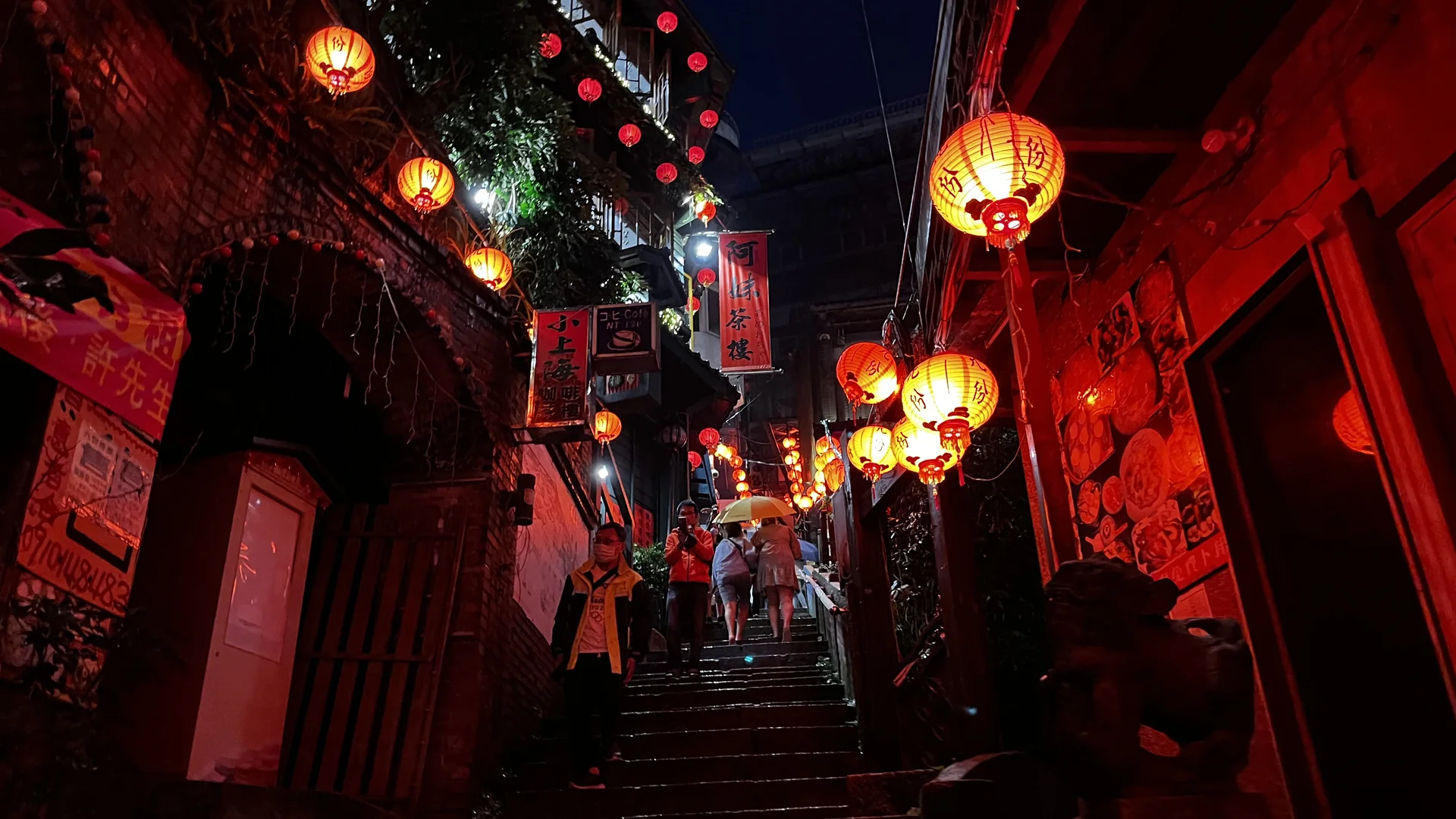 The lantern-lit stone stairway of Jiufen Old Street at night, red paper lanterns strung above teahouses and shopfronts